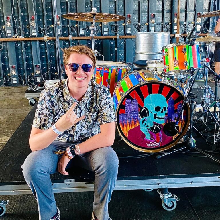 hunter freese seated next to a drum set with his logo on it